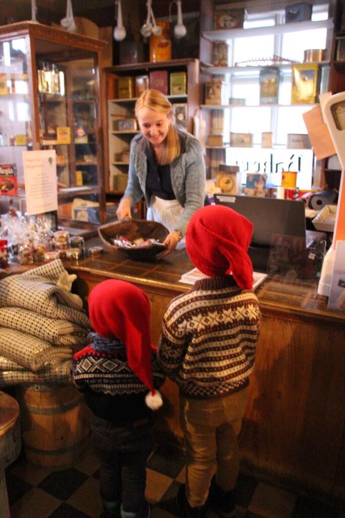 Også i år åpnes butikken i Berggården til førjulshygge. Bildet er fra 2018 med butikkjomfru Renate Strand med to små kunder.
