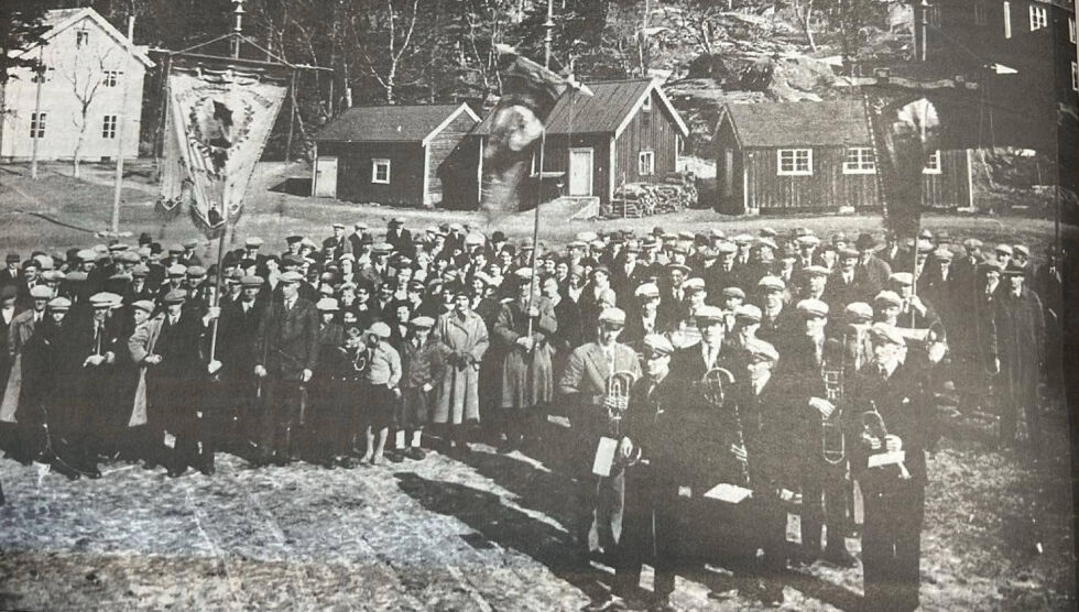 Dette bildet er tatt på "Hotellsletta" et par år før bombinga og viser hvor mye folk det var samlet på 1. mai. Den hvite bygningen var postkontor og sliperikontor. De tre husene i midten er fjøs, uthus og bolig for postmester og kona. Husene ble bombet og postmesteren drept.
 Foto: Ivar Skjærvik